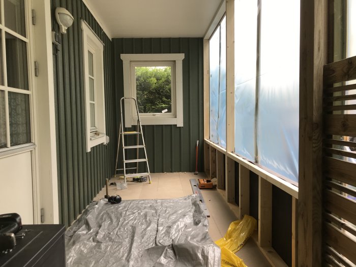 Renovering av rum med delvis avlägsnade foder och exponerade trästommar, stege och verktyg synliga.