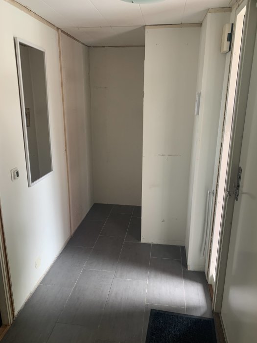 Renoverad hall med grått klinkergolv, vita väggar och dörröppning där garderober tagits bort.