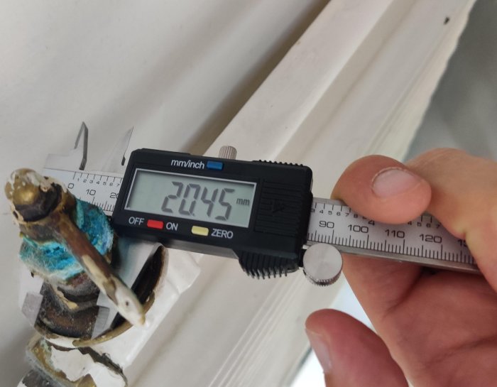 Mätmätare som visar 20,45 mm mätt på en gammal rostig ventils skaft.