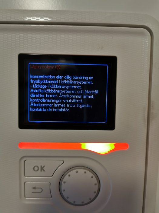 Panele med larm för lågtryck på en värmepump, instruktioner för åtgärder visas på displayen.