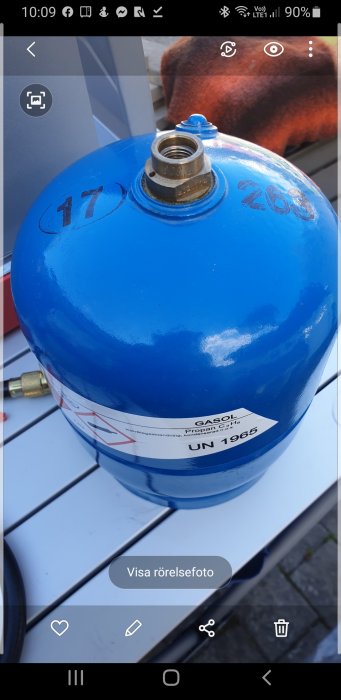 Blå gasoltub med mässingsventil och etikett, som inte passar till ny grillmunstycke.