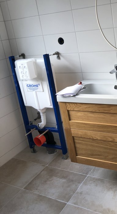 Blå fixtur för VVS-installation i badrum bredvid handfat, redo för inklädnad och kakling.