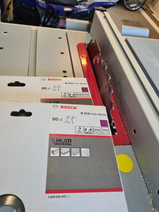 Närbild på nya sågklingor från Bosch bredvid en röd sågbladsskydd på en bordssåg.