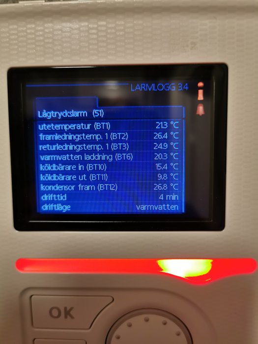 Display på värmepump som visar larmlogg och temperaturvärden med en röd larmindikator tänd.