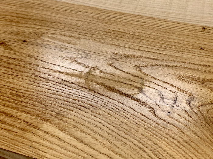 Träbräda med synliga repor och fläckar efter att ha rengjorts från kaffefläckar och rödvin.