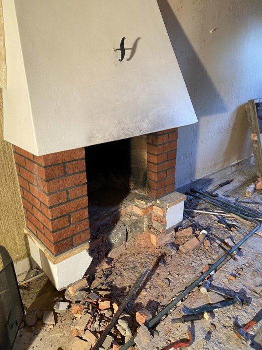 Delvis nedmonterad spis med synliga tegelstenar och murbruk på golvet under renovering.