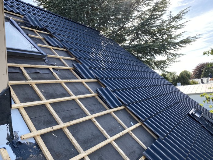 Nyinstallerat takfönster på en takkonstruktion med mörka takpannor och synlig takstol.