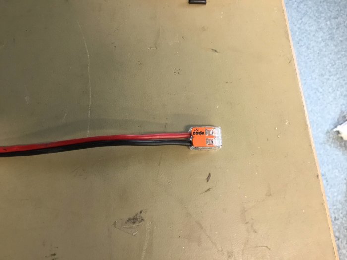 Röd och svart kabel ansluten till en WAGO 221-2 kontakt på en bordsskiva.