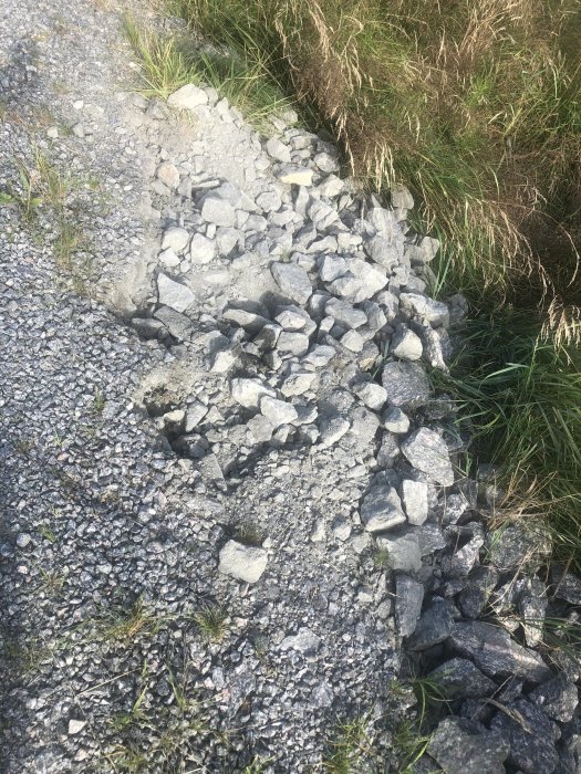 Grusvägskant med mystiska hål och uppkastat grus, potentiellt orsakade av ett vilt djur på natten.