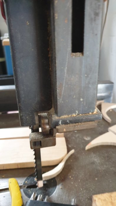 Närbild av öppen bandsåg med synlig sågblad och delvis demonterat bandstöd.