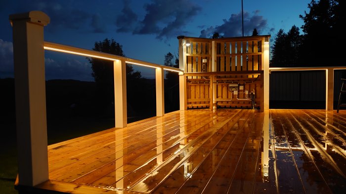 Nyligen byggd träaltan med integrerad belysning i skymningen, våt yta reflekterar ljus.