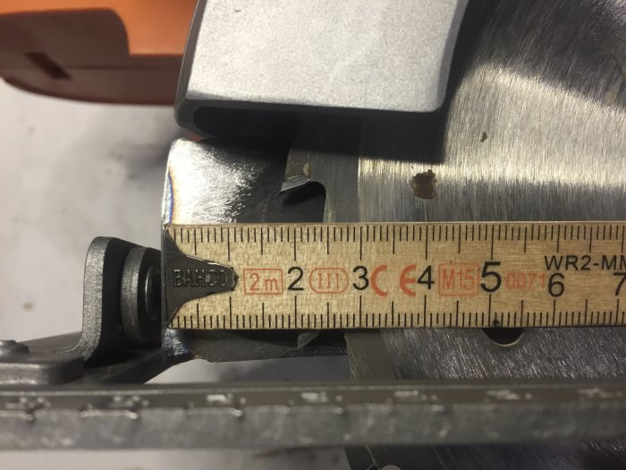 Mätning av sågbladets tjocklek med ett skjutmått mot en cirkelsågsklinga.