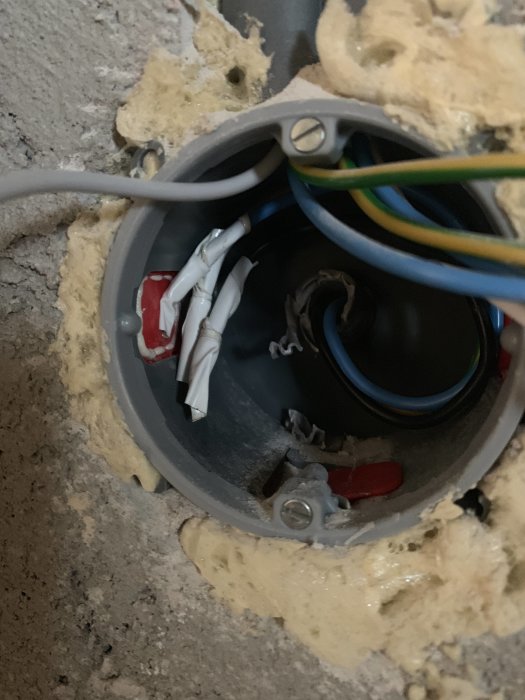 Öppen eldosa med flera kablar inklusive en två-ledare och isoleringstejp i en vägg.