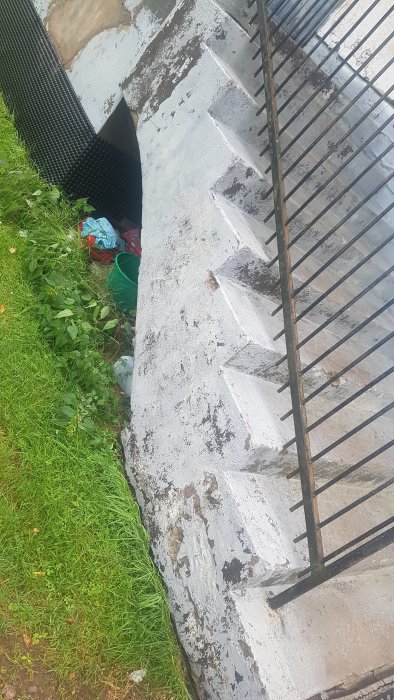 Vägg och trappa som visar tecken på slitage efter högtryckstvätt, med behov av reparation och puts.