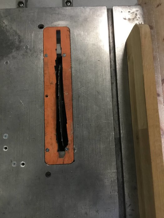 Del av såg med orange brytarknapp och klinga synlig, monterad på ett grått metallstativ.