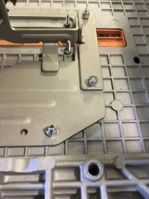 Närbild av en sågstation med stor röd brytare och försänkta M5 skruvar på en metallbas.