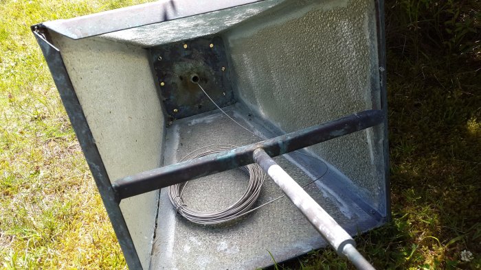 Close-up of the interior of a metallic post showing a coiled wire and a metal rod extending towards the opening, part of a repair process.