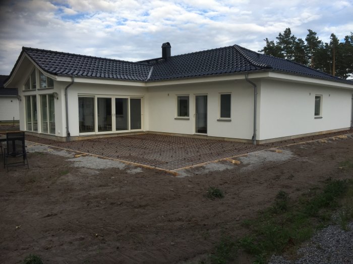 Ett nybyggt enfamiljshus med terrass under konstruktion och 8mm tjocka mattor utlagda på marken.