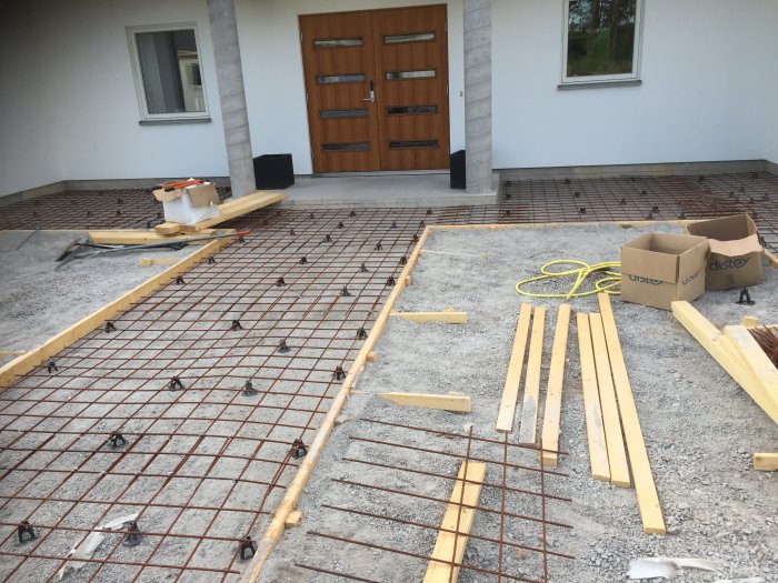 Armeringsnät och träreglar på betongunderlag i pågående byggprojekt för golvkonstruktion.