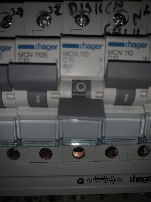 Närbild av en eltavla med flera säkringar från Hager, handskrivna anteckningar syns ovanpå.