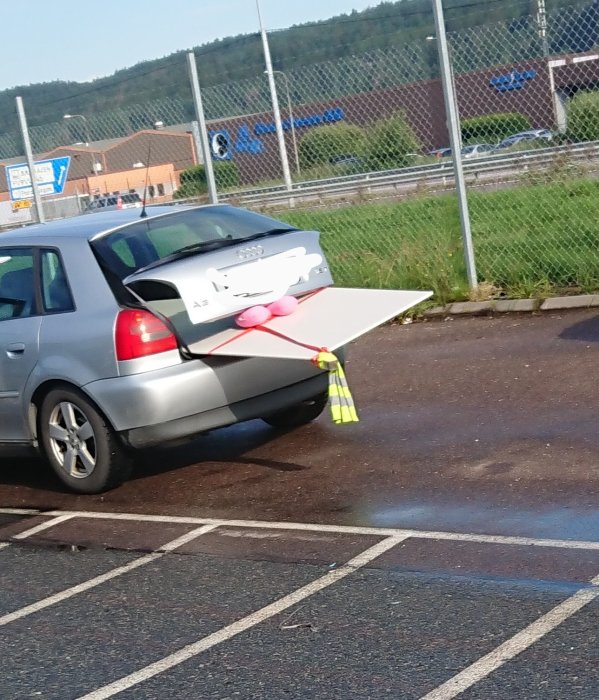 En nackkudde används som stötdämpare på en bil med öppen baklucka som transporterar en stor platt föremål.