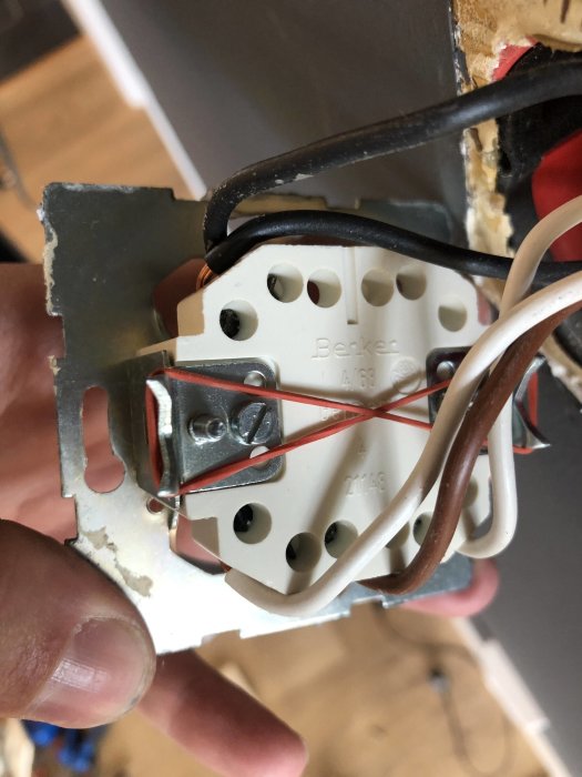Nya elektriska brytaren kopplad med flera kablar och fastsatt i dess väggdos.