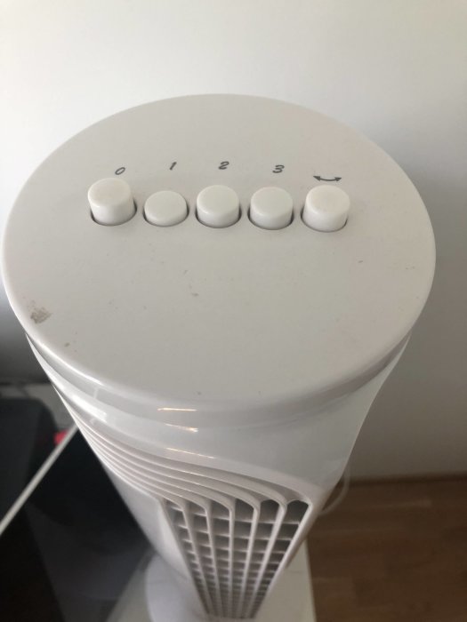 Toppdel av vit pelarfläkt med hastighetsknappar märkta 0, 1, 2, 3 och en svängningsknapp.