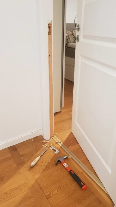 Nyinstallerad dörr till sovrum med delvis avlägsnad karm och verktyg på golvet.