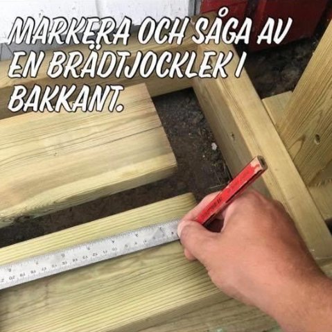 Närbild av en hand som markerar mått med penna på en träbjälke vid konstruktion av däck.