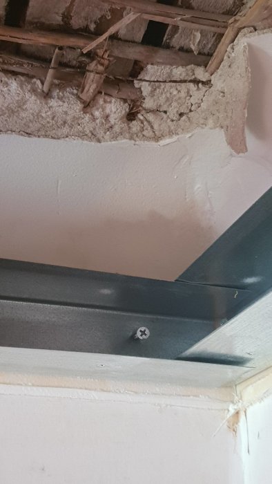 Skruvar i ett vitmålat innertak genom att använda neodymmagneter, med synligt takgips och träbjälkar.