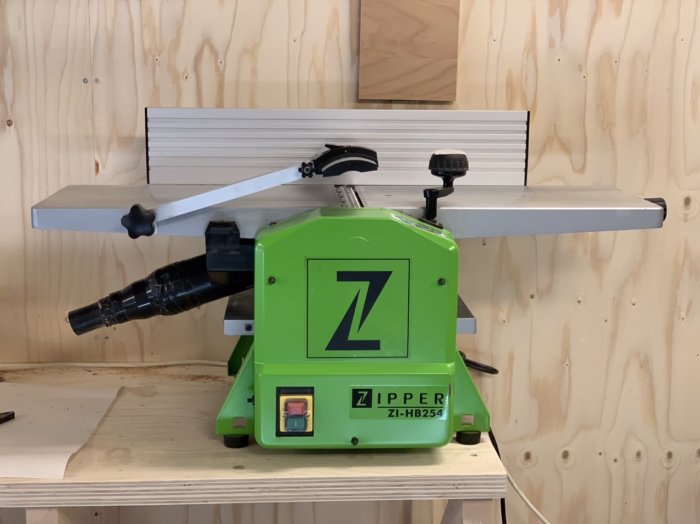 Grön Zipper ZI-HB254 rikt- och planhyvel på ett arbetsbord mot trävägg.