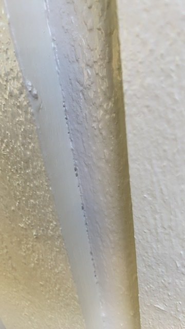 Närbild av nymålad träpanel i vitt med synlig fog mellan brädorna.