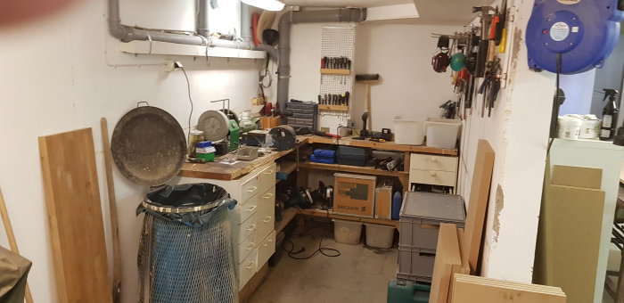 Översikt av rörigt verkstad med verktyg och material utspridda, före renovering och organisering.