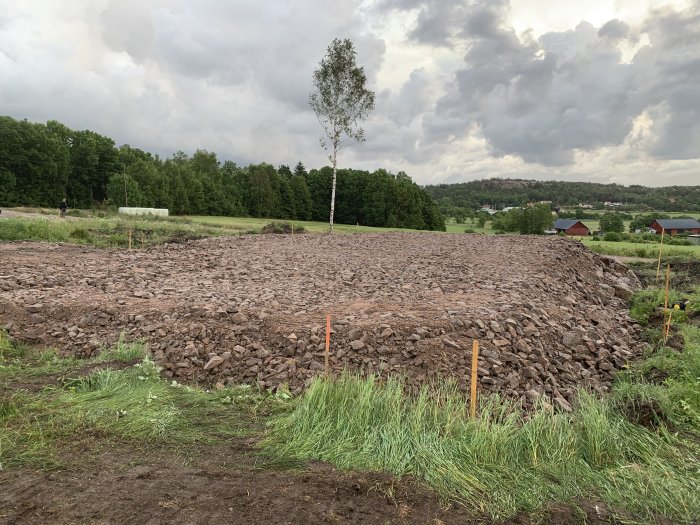 Utlagt lager av större stenar på byggarbetsplats, redo att vältas och täckas med mindre grus.