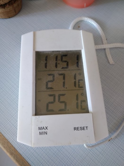 En termometer som visar hög utomhustemperatur på 27,1°C och inomhustemperatur på 25,1°C.