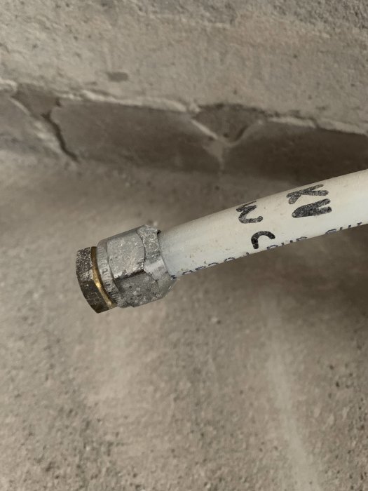 Pex-rör med en metallkoppling mot en betongvägg.