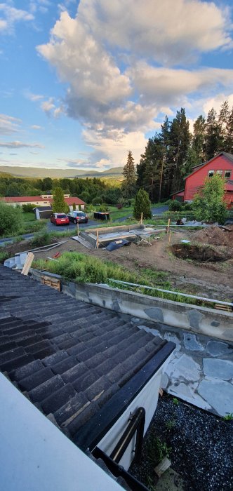 Uppbyggnad av växthusgrund med jämnad sand, markduk, grus, ringmur av cementblock och regnvattenstank.