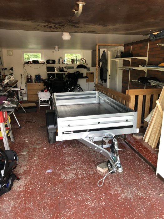Ett nytt släpvagn i ett garage med verktyg och cyklar i bakgrunden.