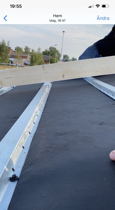 Rak planka på stålläkten över gammalt papp på tak som visar ojämnheter.