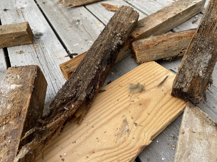 Nedrivna träfibrer och bitar av trasigt trämaterial på ett plankgolv efter en husrenovering.