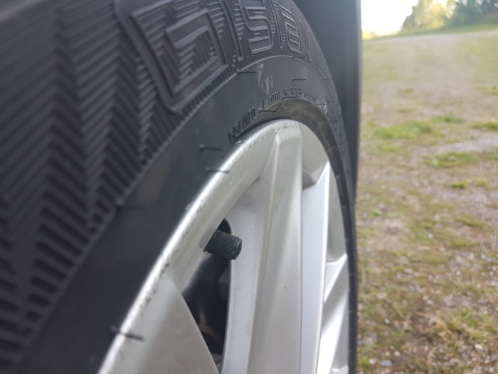 Närbild av ett bildäck som ser ut att sticka ut över kanten på en vit bilfälg.