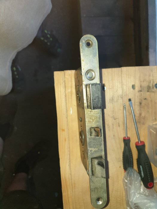 Symmetriskt dörrlås monterat på träyta med måttet 35mm på båda sidor, verktyg synliga i bakgrunden.