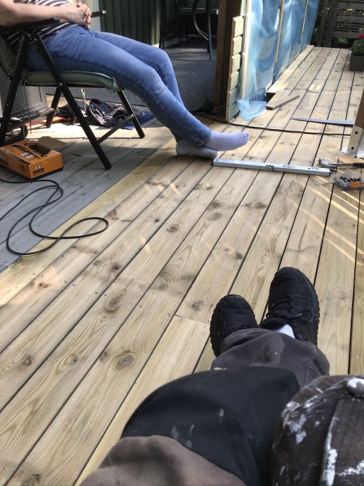 Trallgolv utomhus med delvis omvända träplankor för uppfräschning, verktyg och person delvis synliga.