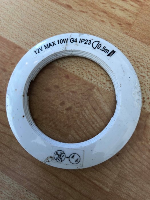 Använd ringformad transformator märkt med "12V MAX 10W G4 IP23" mot en träbakgrund.