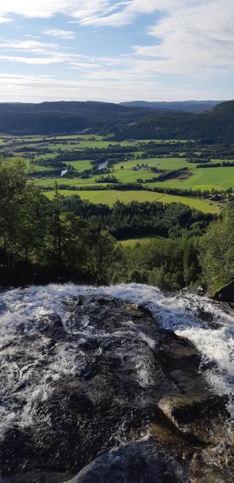 Vy över gröna fält från Römmesfossen vattenfall i Fosen, Norge.