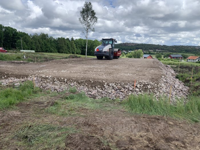 Valtat byggområde med stenlagret 0-90, traktor i bakgrunden, samt utsättningspinnar markerade.