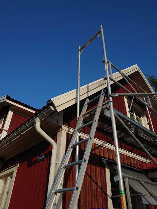 Renoverad övre del av vindskiva och borttaget fågelbo syns på hus med stege lutad mot fasaden.