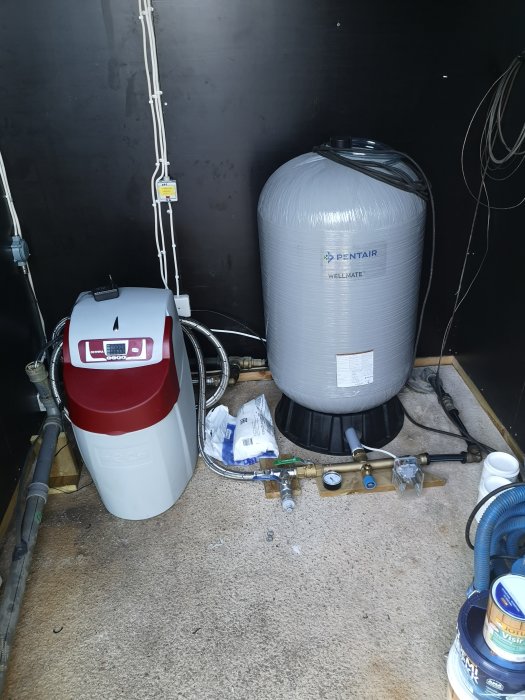 Installation av ett vattenfilter och en hydrofor i ett förrådsutrymme, komplett med rörledningar och mätutrustning.