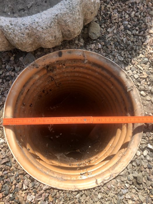 Måttband över öppningen av en dagvattenbrunn som visar en diameter på cirka 340 mm.