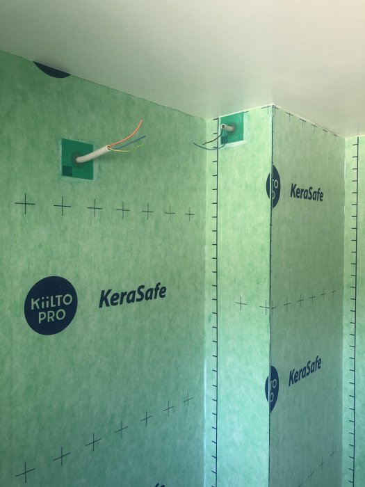 Vägg i badrum klädd med grönt tätskikt och utstickande elledningar samt förberett för våtrum.